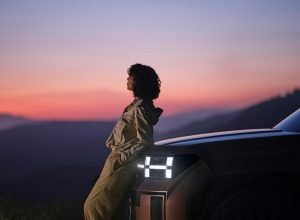 a woman sitting on the hood of a car